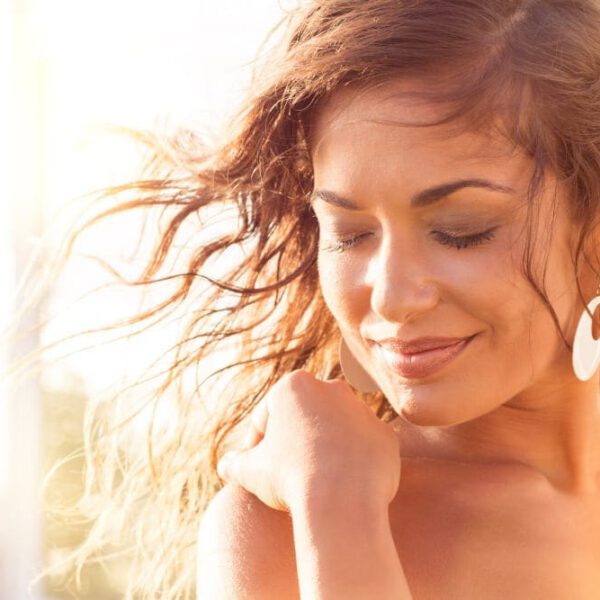 Close up of smiling woman with her hair blowing in the breeze during sunset.