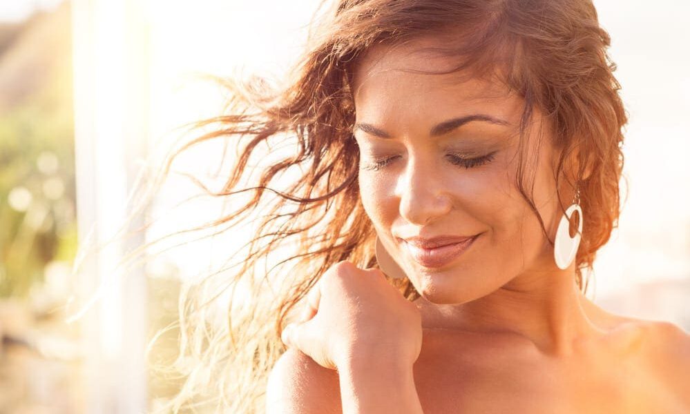 Close up of smiling woman with her hair blowing in the breeze during sunset.