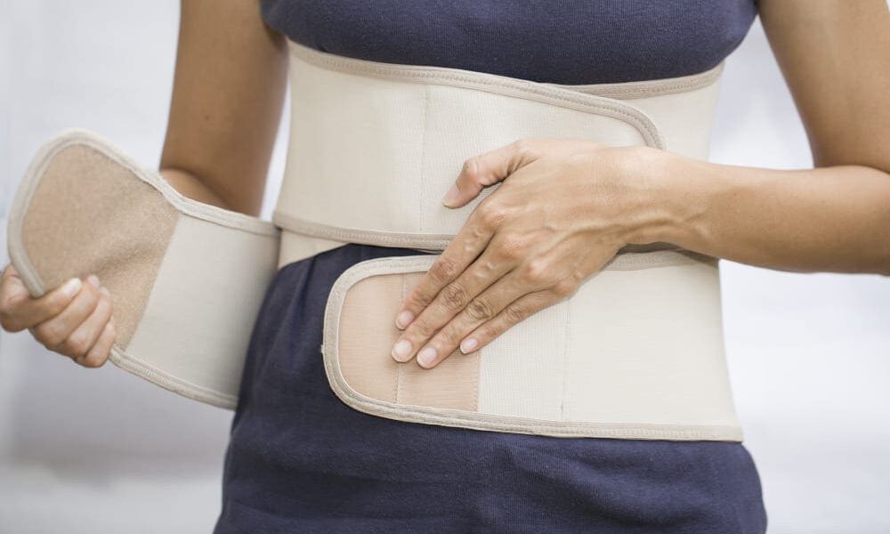 woman's wrapping her midsection with a compression garment.