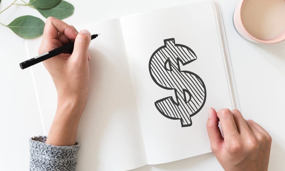 Close up of hands holding pen, drawing a dollar sign.