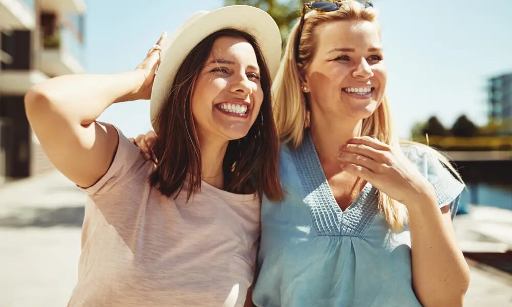 Two female friends enjoying a day outside together discussing breast augmentation.