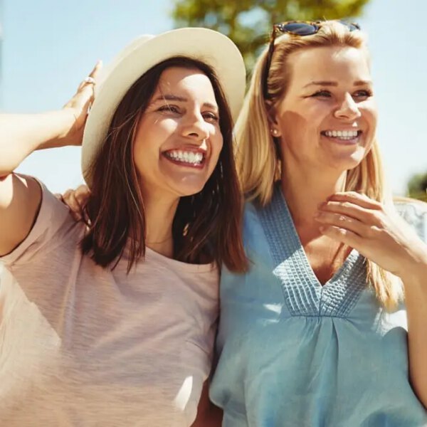 Two female friends enjoying a day outside together discussing breast augmentation.